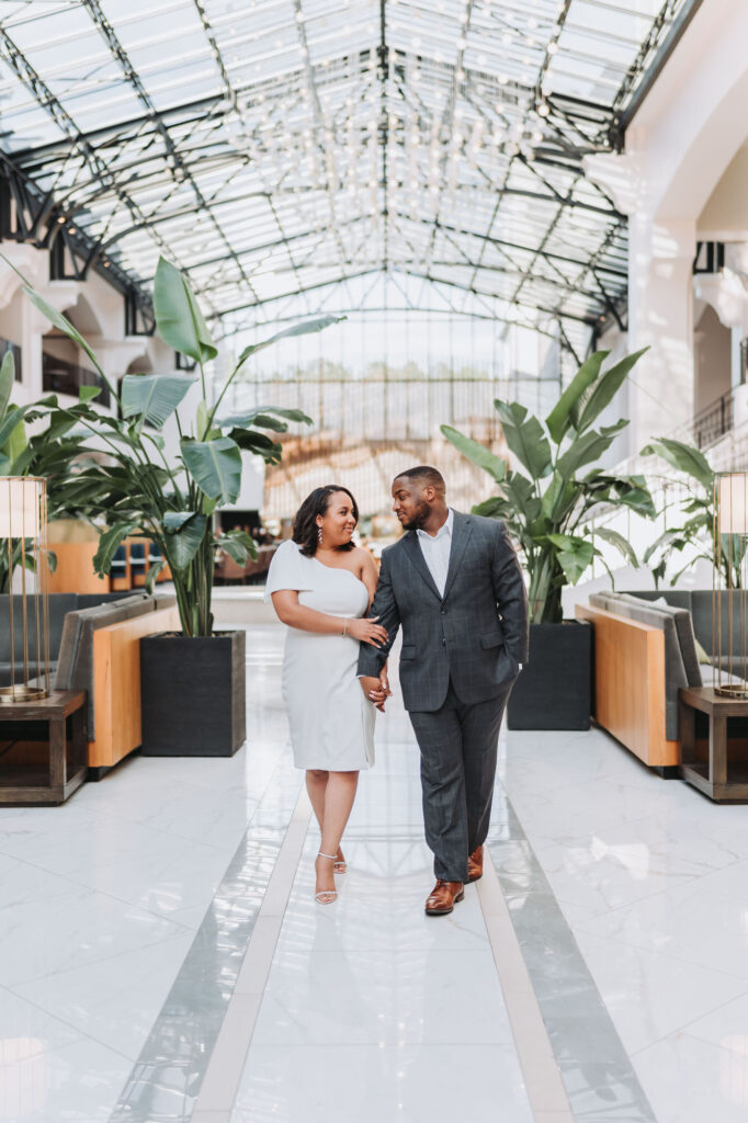 Man and woman walk while holding hands in Chateau Elan for their engagement photos.