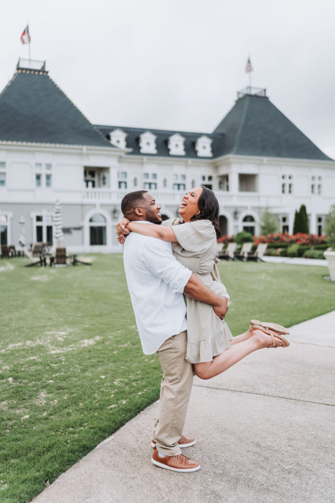 Man picks up woman in front of Chateau Elan during engagement photos.