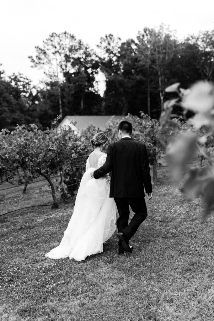 Bride and groom walk through vineyard. Wedding at Koury Farms.