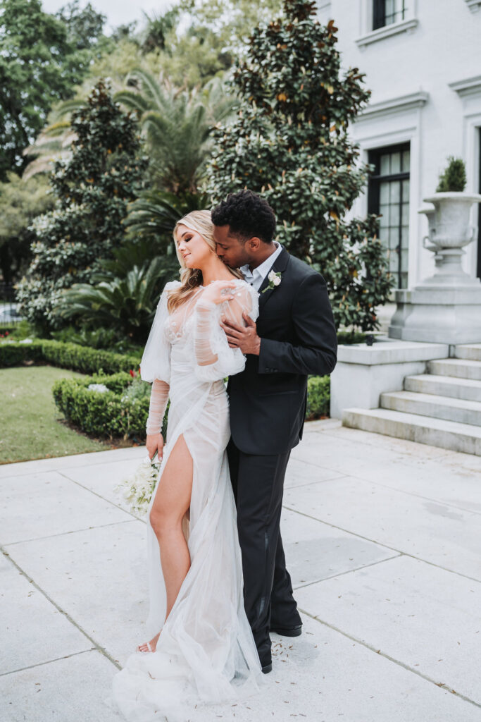 Groom kisses bride's neck at armstrong kessler mansion wedding