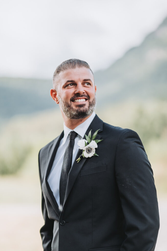 Groom looks off into distance and smiles.