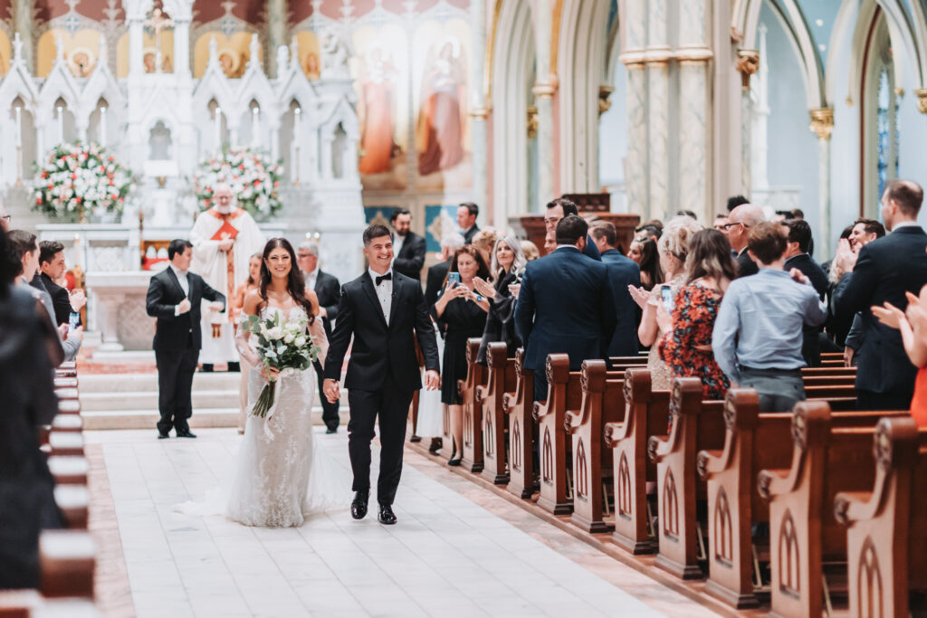 Bride and groom walk down aisle of Cathedral Basilica of St. John the Baptist.