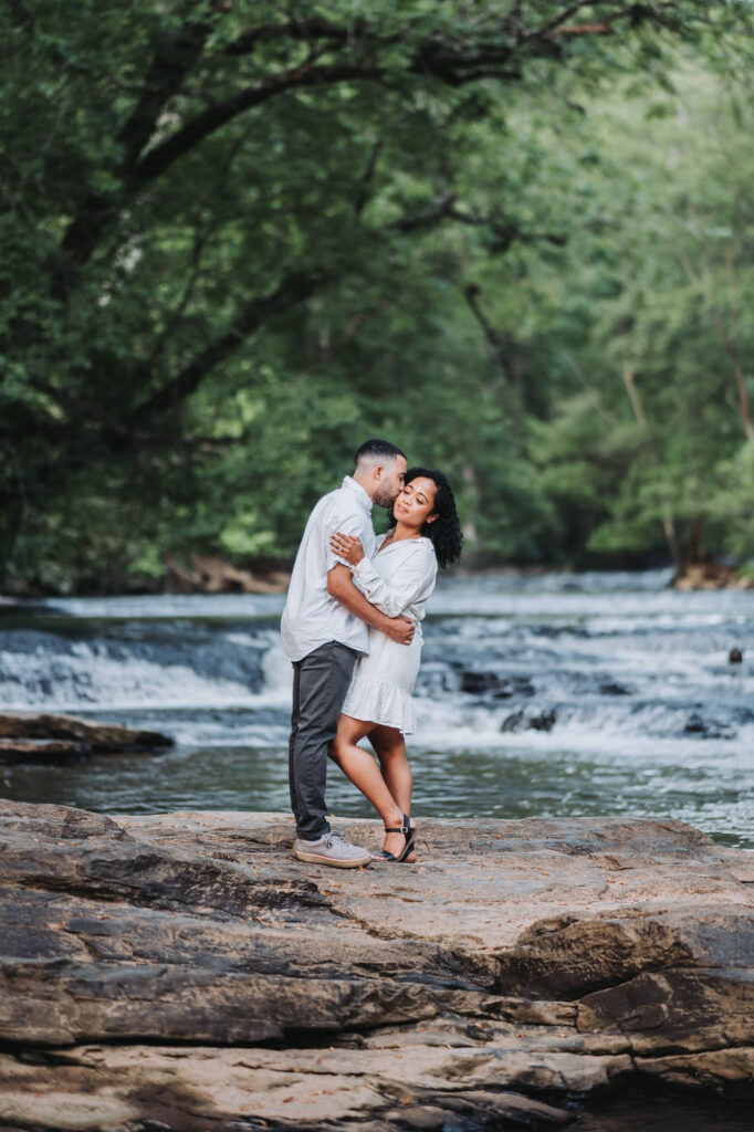 Guy kisses girl's cheek during their roswell mill engagement session photoshoot.