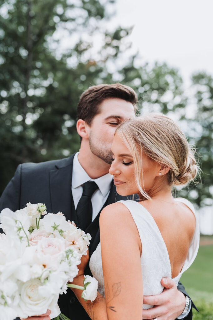 Groom kisses bride's cheek at their Lake Lanier Legacy Pointe wedding
