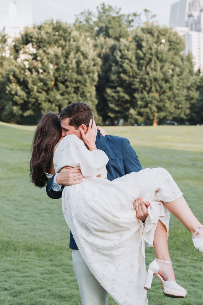 Guy scoops girl up in his arms during their Piedmont Park Atlanta engagement photoshoot.