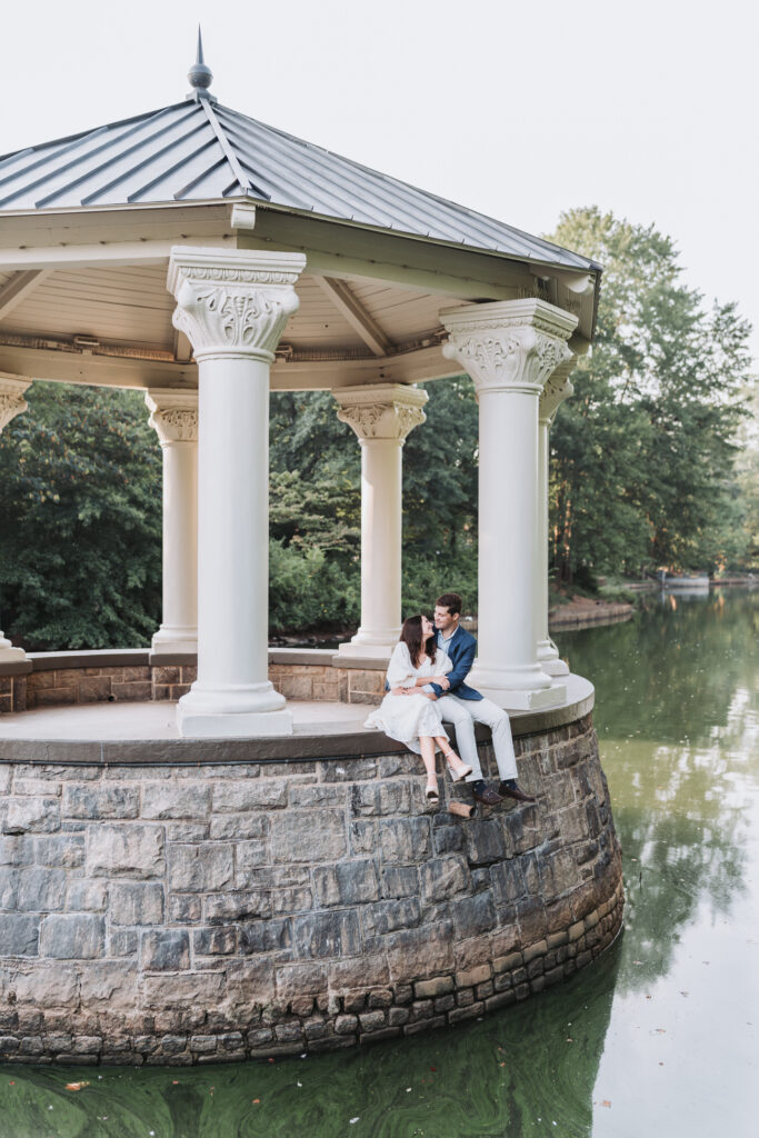 Man and woman sit at the gazebo at Piedmont Park during their engagement shoot