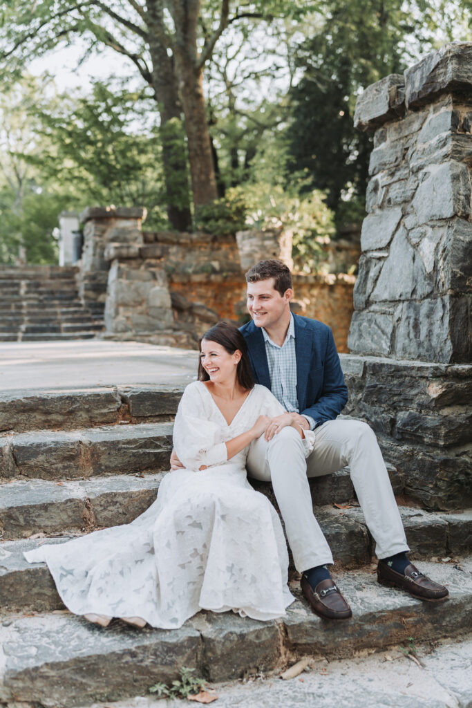 Man and woman sit on staircase during Piedmont Park engagement shoot