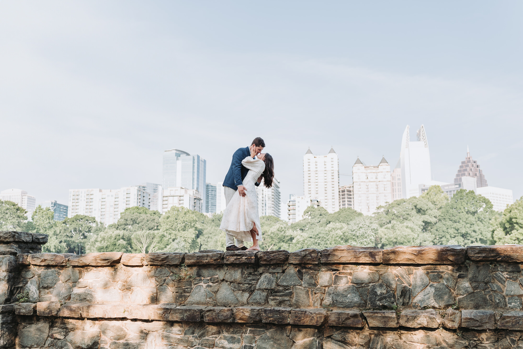 Engagement session at piedmont park. Engaged couple is kissing with the city view in the background.