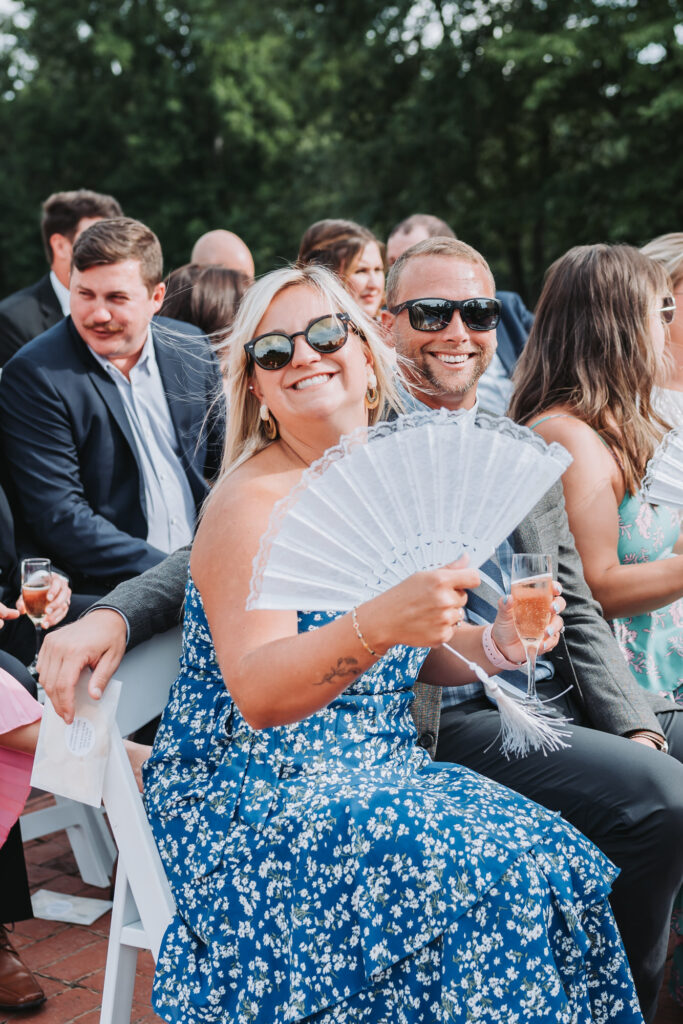 Guest fans themselves during a summer ceremony Wedding at Sanctuary Estates in Georgia.