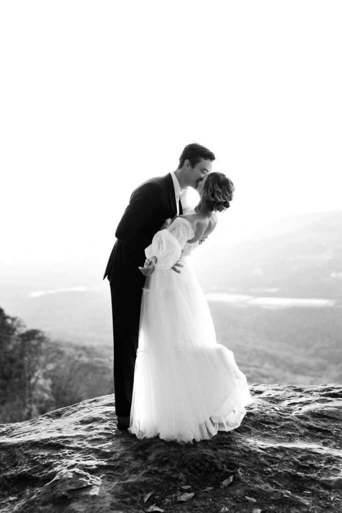 Couple photographed in black and white kissing on a bluff