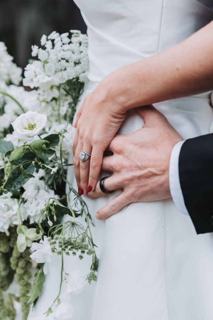 close up photo of a bride and groom hands and wedding rings