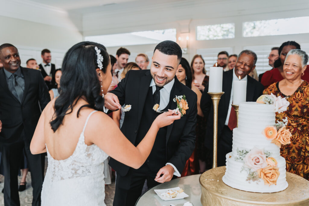 Groom feeds bride wedding cake.