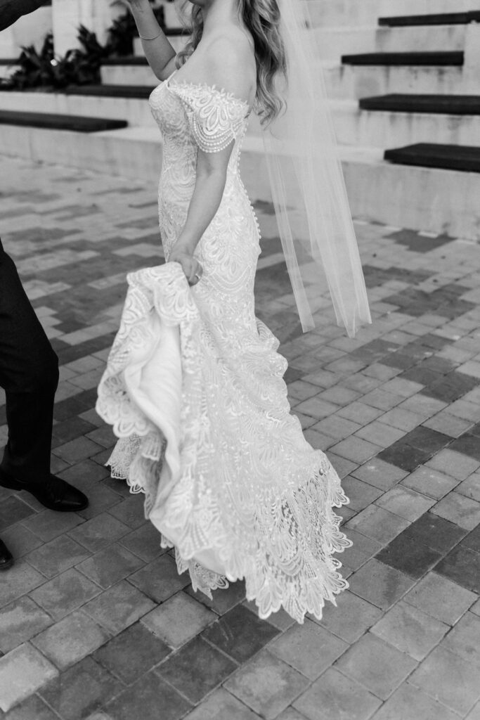 Bride holds dress as groom twirls her.