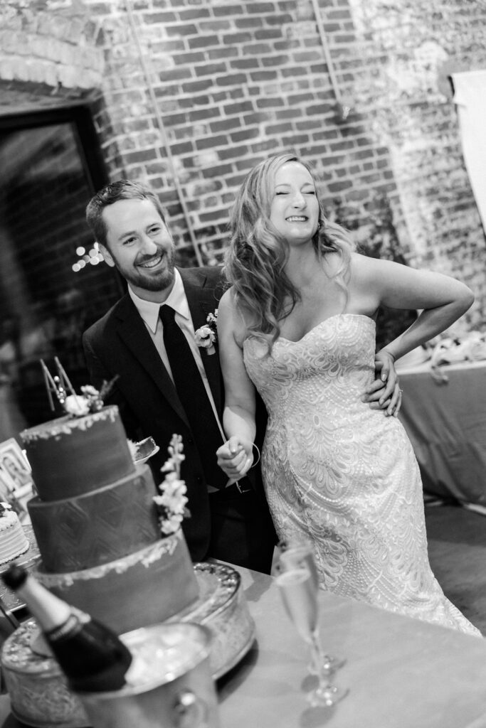 Bride and groom laugh as they cut wedding cake