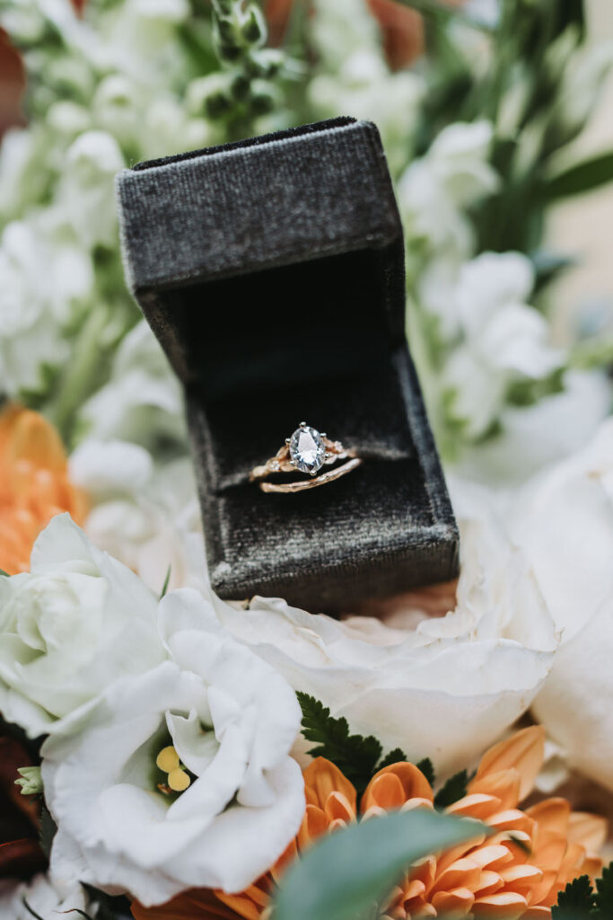 up close photo of engagement ring in ring box with flowers.