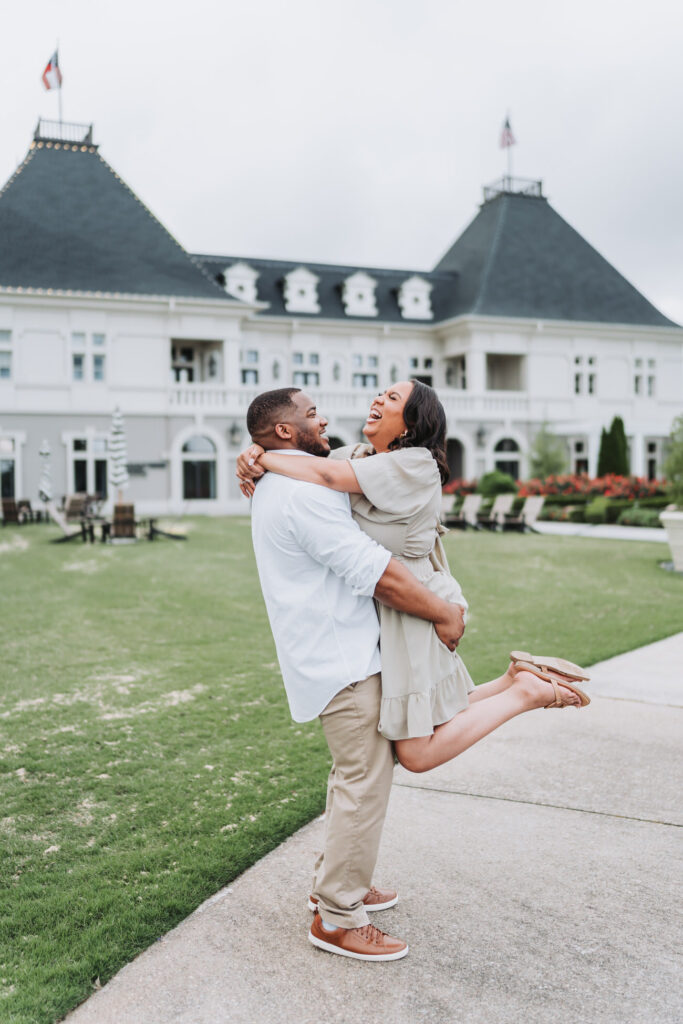 guy picks up girl in front of Chateau Elan during engagement photos