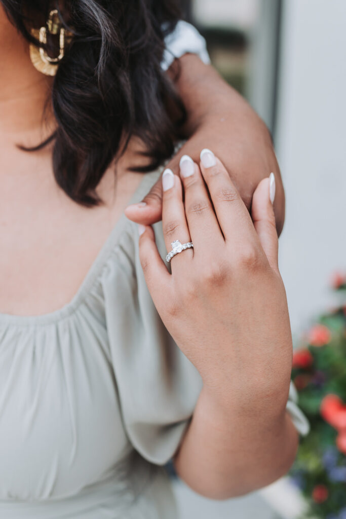up close photo of girl holding guys hand with her engagement ring showing