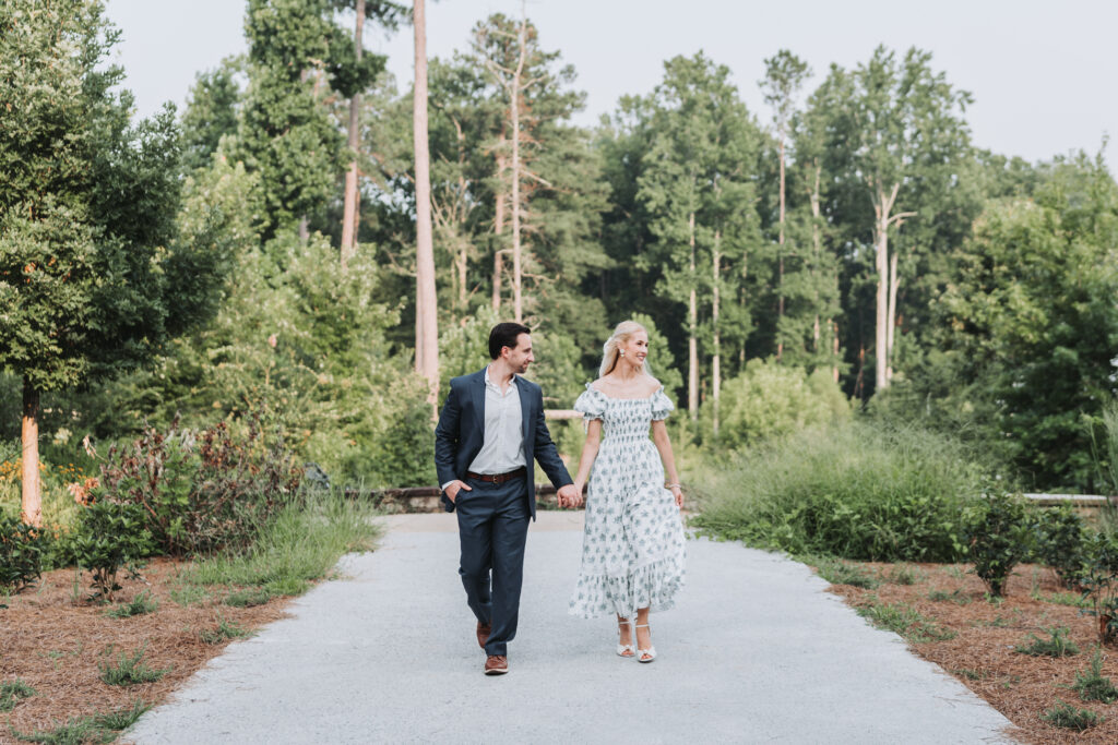 guy and girl walk towards camera while holding hands during their engagement session.