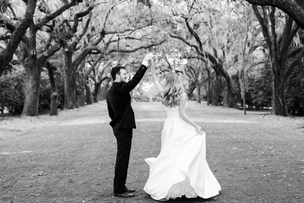 Groom spins bride in Avenue of Oak trees at Legare Waring House