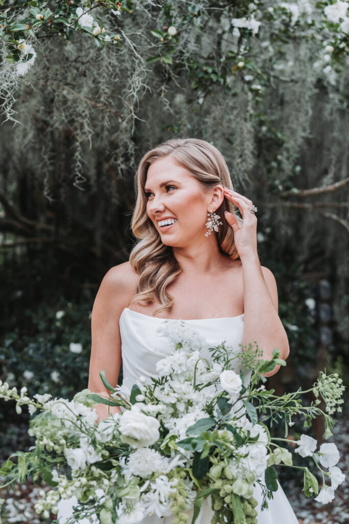bride brushes her hair back while holding her bouquet