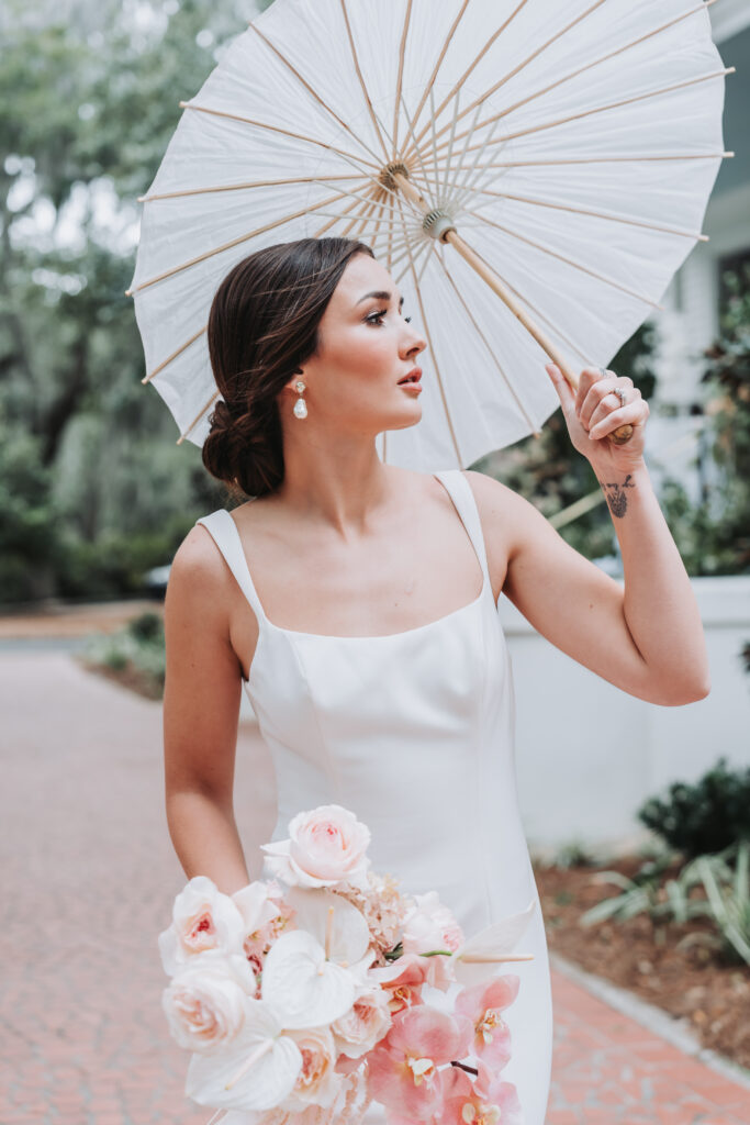 Bride holds umbrella as wind blows through her hair