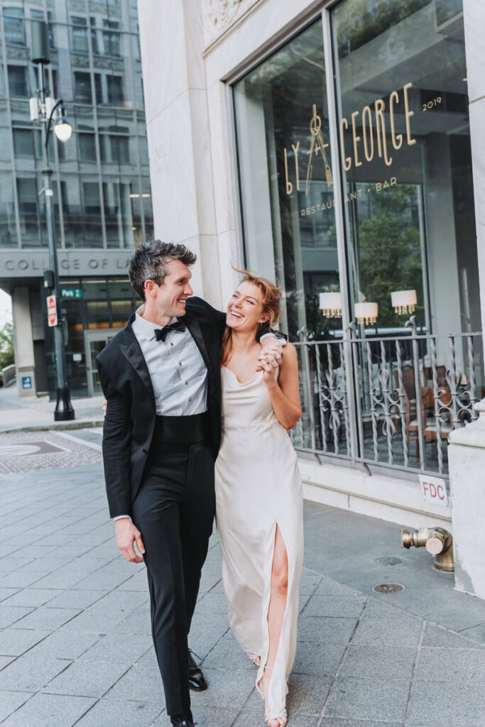 guy has arm around girl as they walk and laugh.