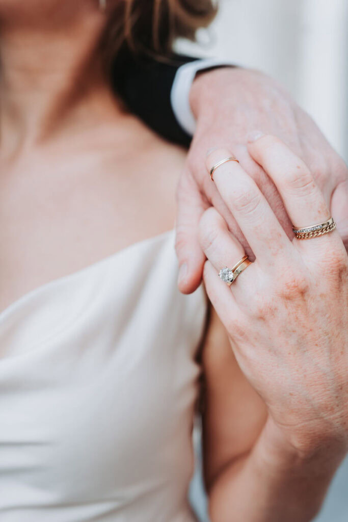 closeup of engagement ring as girl and guy hold hands.