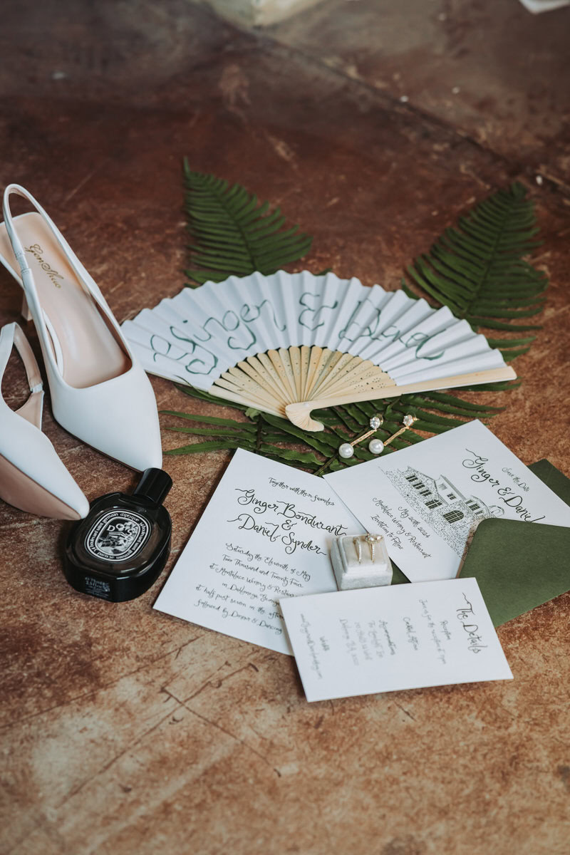 simple wedding flat lay with invitations and green accents.