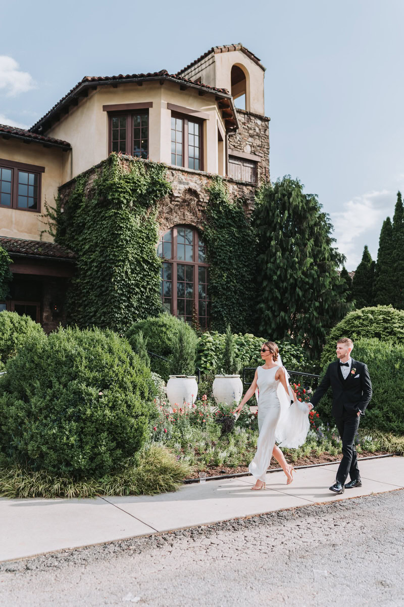 bride and groom hold hands while walking in front of Montaluce Winery Wedding venue.