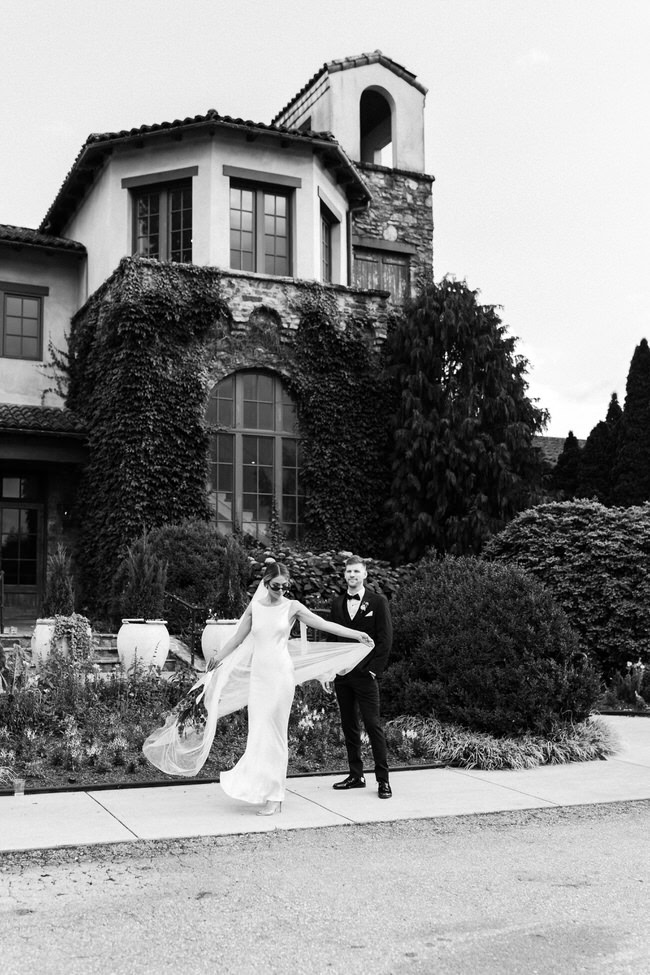 bride twirls in front of montaluce winery while groom looks at her