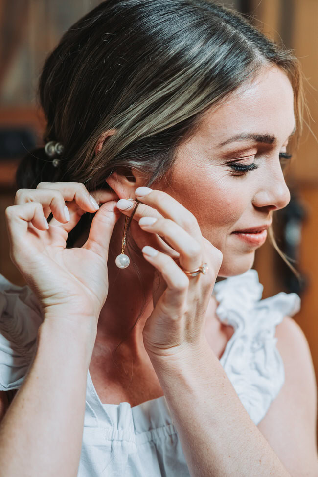 bride puts on wedding earrings