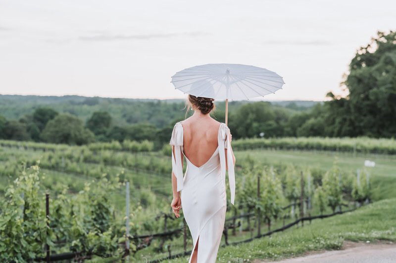 bride faces the Montaluce vineyard while holding an umbrella.