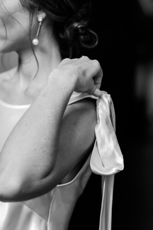 bride adjusts bow straps on her dress.