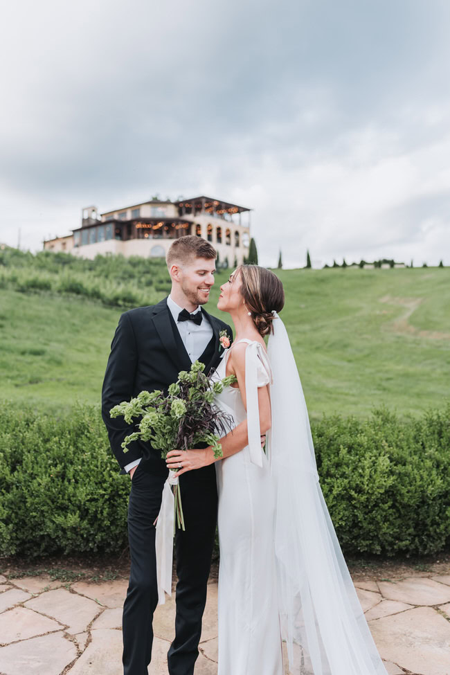 bride and groom look at each other with Montaluce winery in the background.