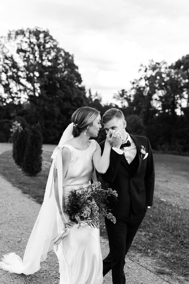 groom kisses bride's hand while walking