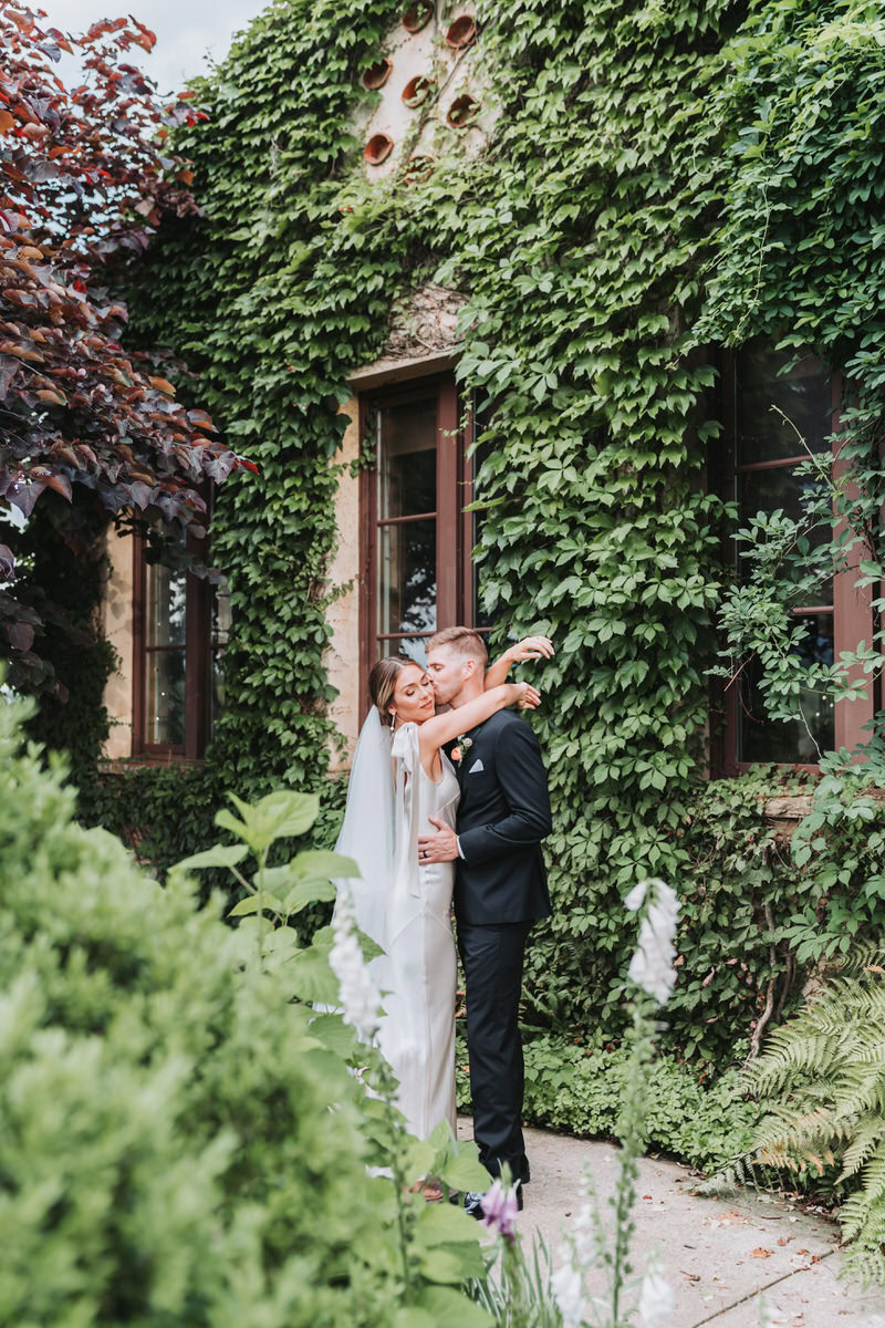 bride throws arms around groom and he kisses her cheek.