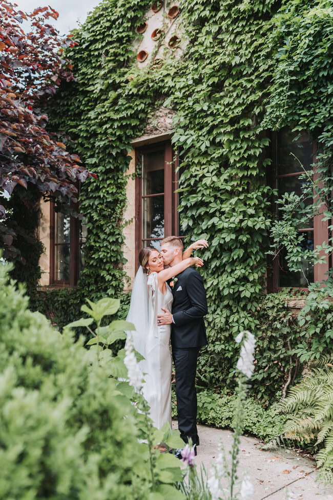 bride throws her arms around groom while he kisses her cheek.