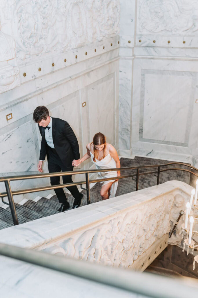 woman and man walk up the grand staircase at candler hotel.