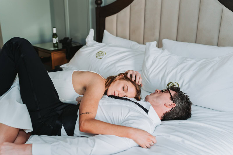 girl rests her head on guys chest while they lay on the bed.