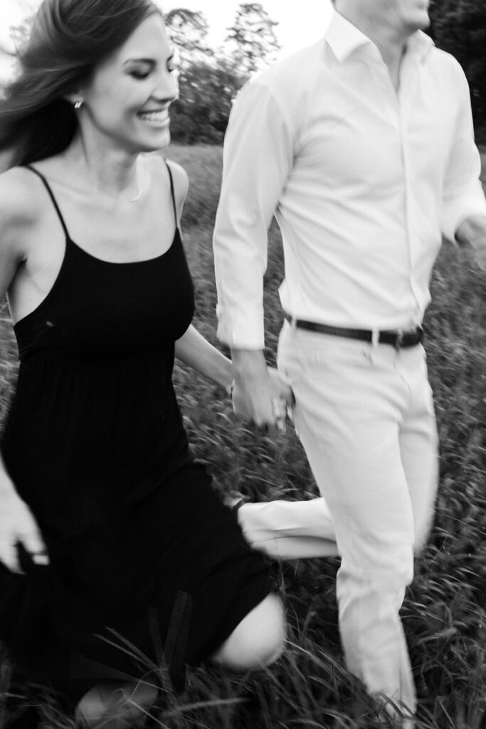 up close photo of couple holding hands and running through the field.