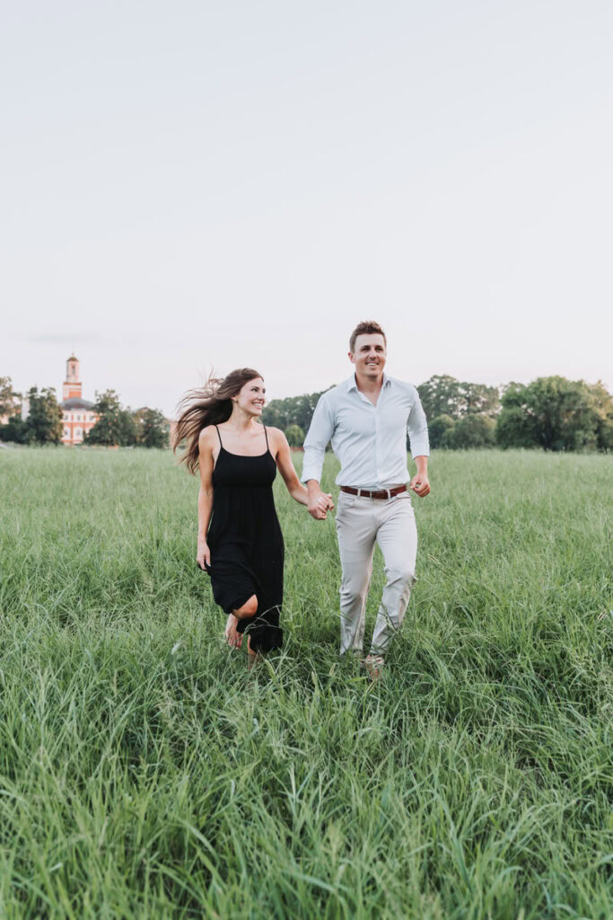 couple holds hands and runs through the field for their Berry College Engagement photos