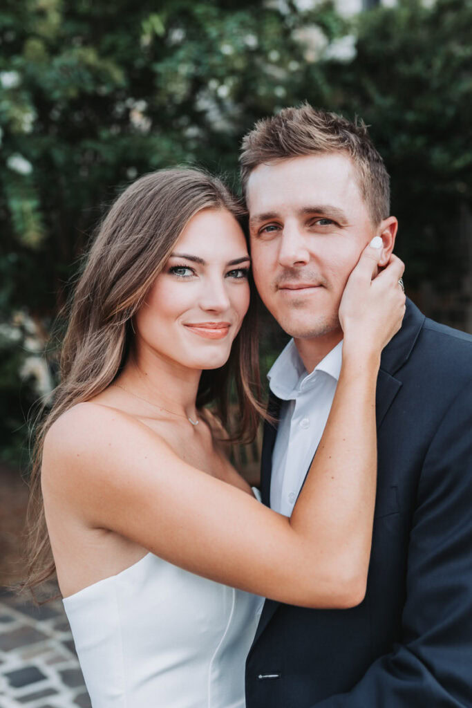 girl and guy look at camera as she holds his face for their European inspired engagement photos