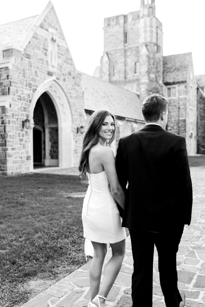 girl looks back as she holds guys hand while they walk on Berry college campus