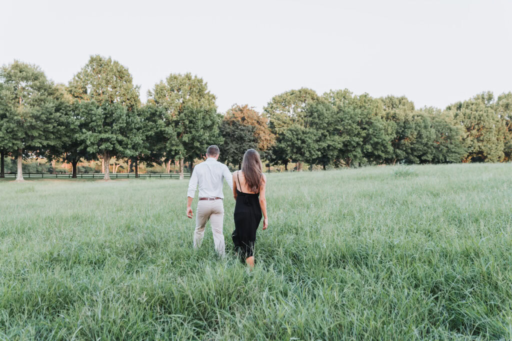 guy holds girl's hand and pulls her through the field