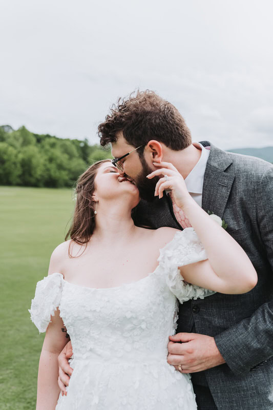 bride pulls groom in for a kiss as he holds her waist