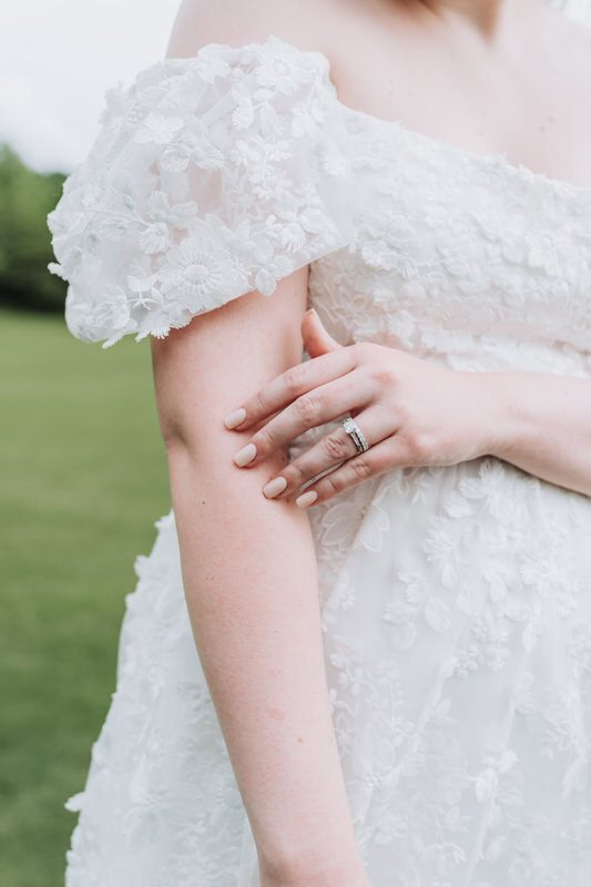 bride touches her arm as she shows off her wedding ring