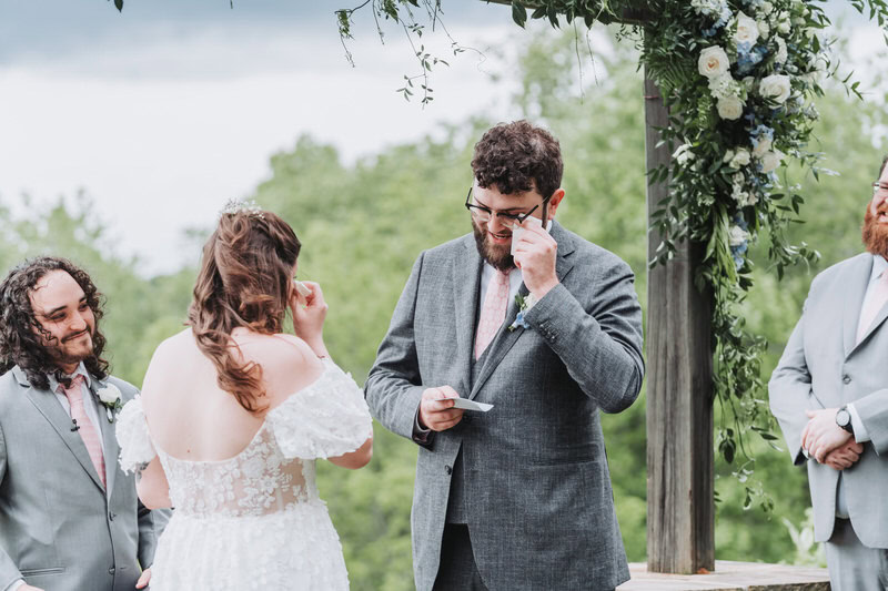 groom wipes tear away from his eyes as he reads his vows