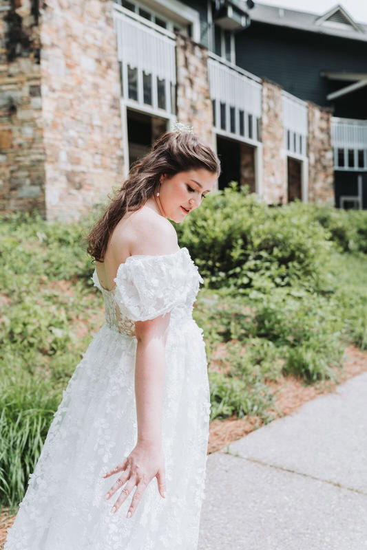 Bride touches her wedding dress while she looks down