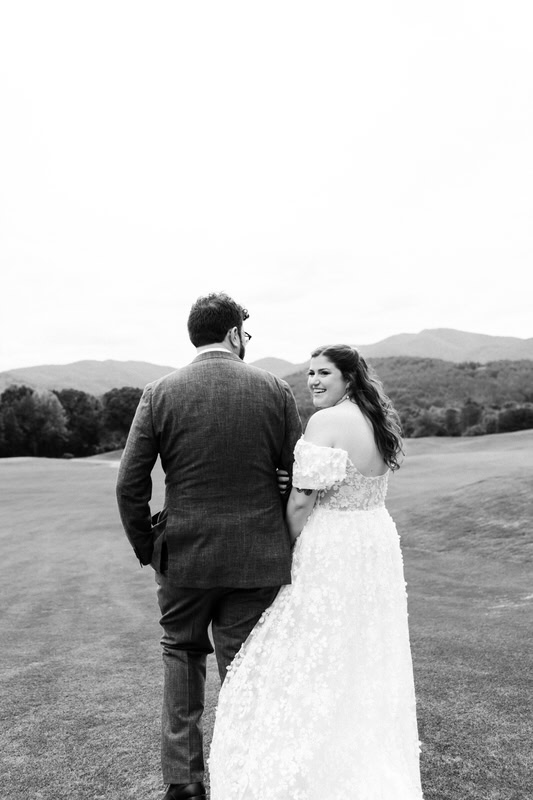 bride looks back at the camera while holding grooms arm as they walk