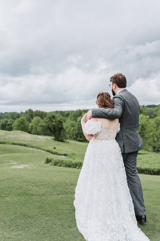 bride and groom walk through the field